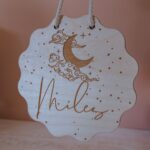 Hanging timber door name sign with cloudy night and moon