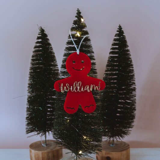 Red gingerbread man with glitter name on Christmas tree